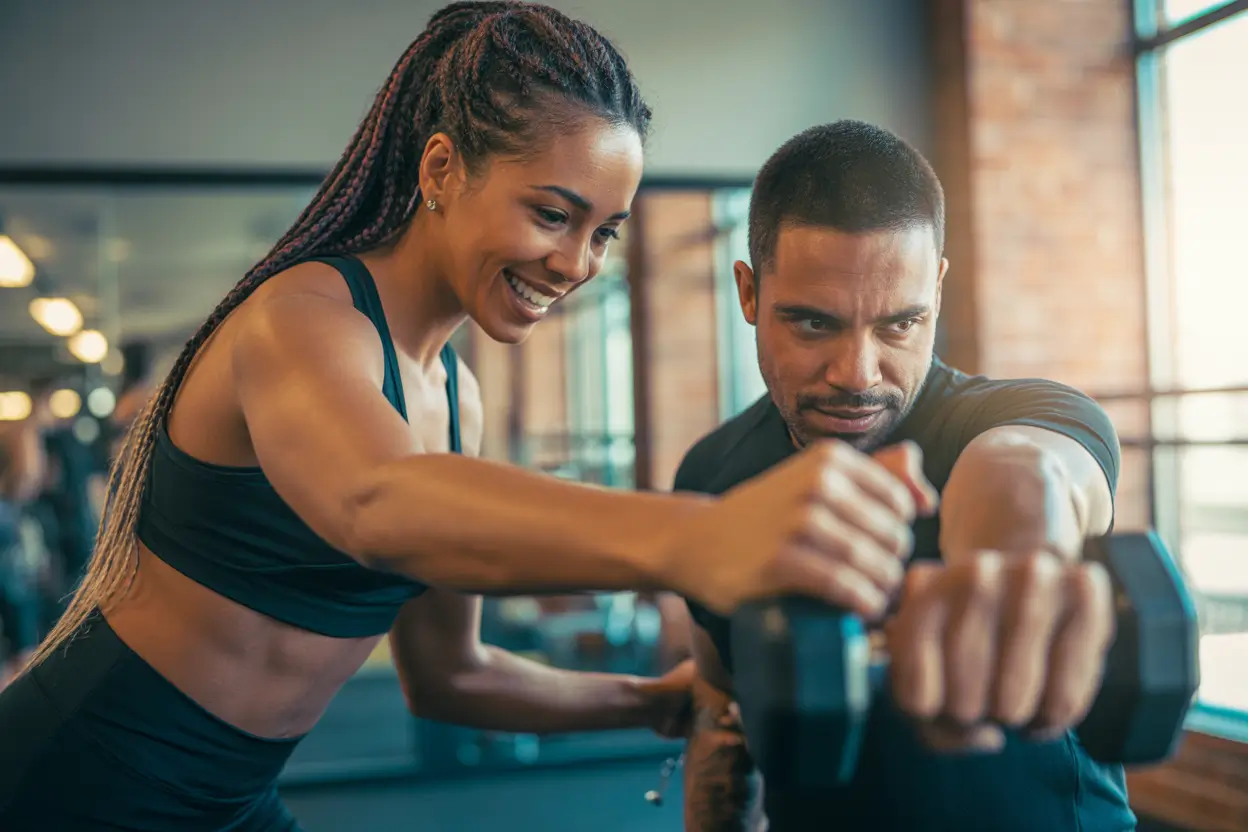 A personal trainer assisting a client with proper form during strength training