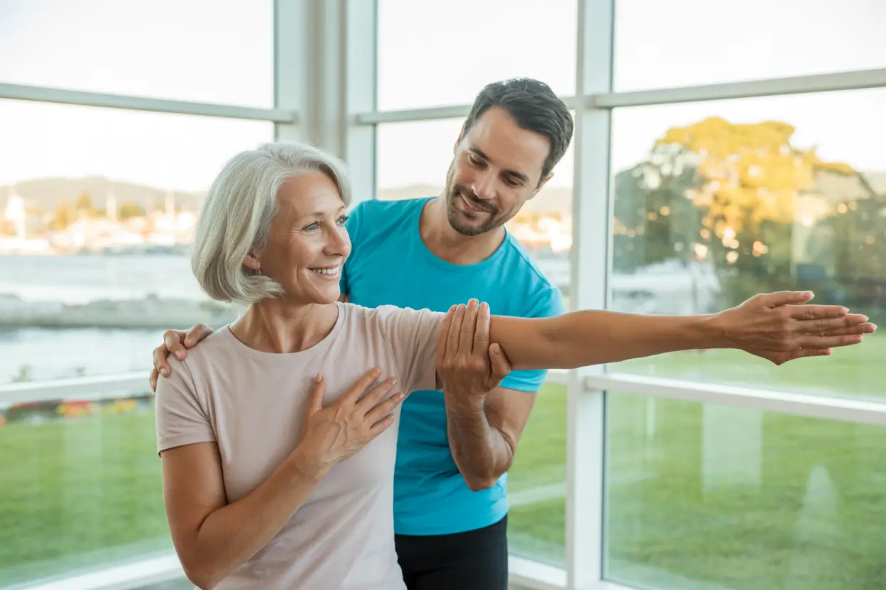 Best Physiotherapist Victoria BC 3 A kind physiotherapist gently guiding a patient through a stretching exercise in a bright modern clinic in Victoria BC
